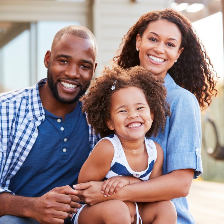 Family posing in front of a house